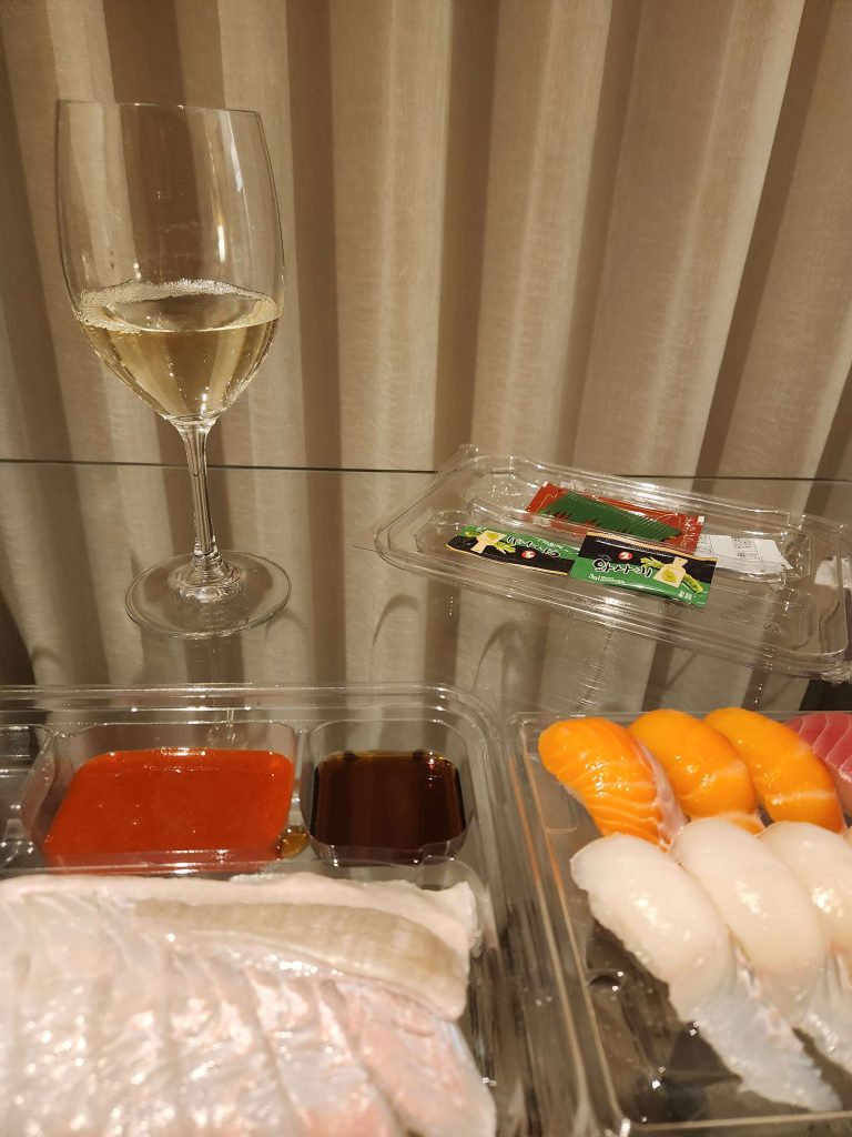 sushi and white wine on a table in a quiet hotel room