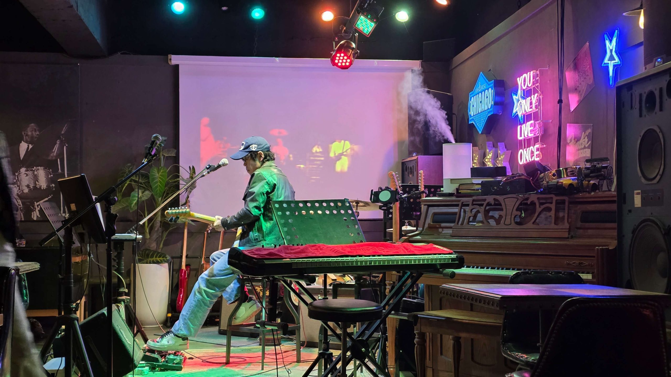 Live music bar scene with a guitarist playing under colorful lights, capturing a quiet pause moment