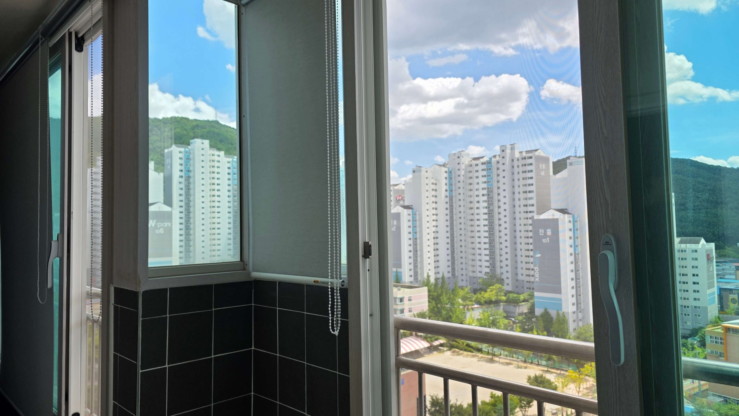 Soft wind flowing through an open window, with morning light over a quiet city and hills.