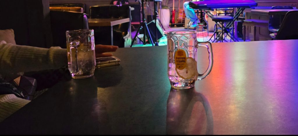 Two highball glasses on a table in a live music bar, reflecting a calm and quiet moment