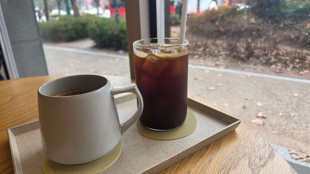 two cups of coffee on a table by the window with a calm street view outside