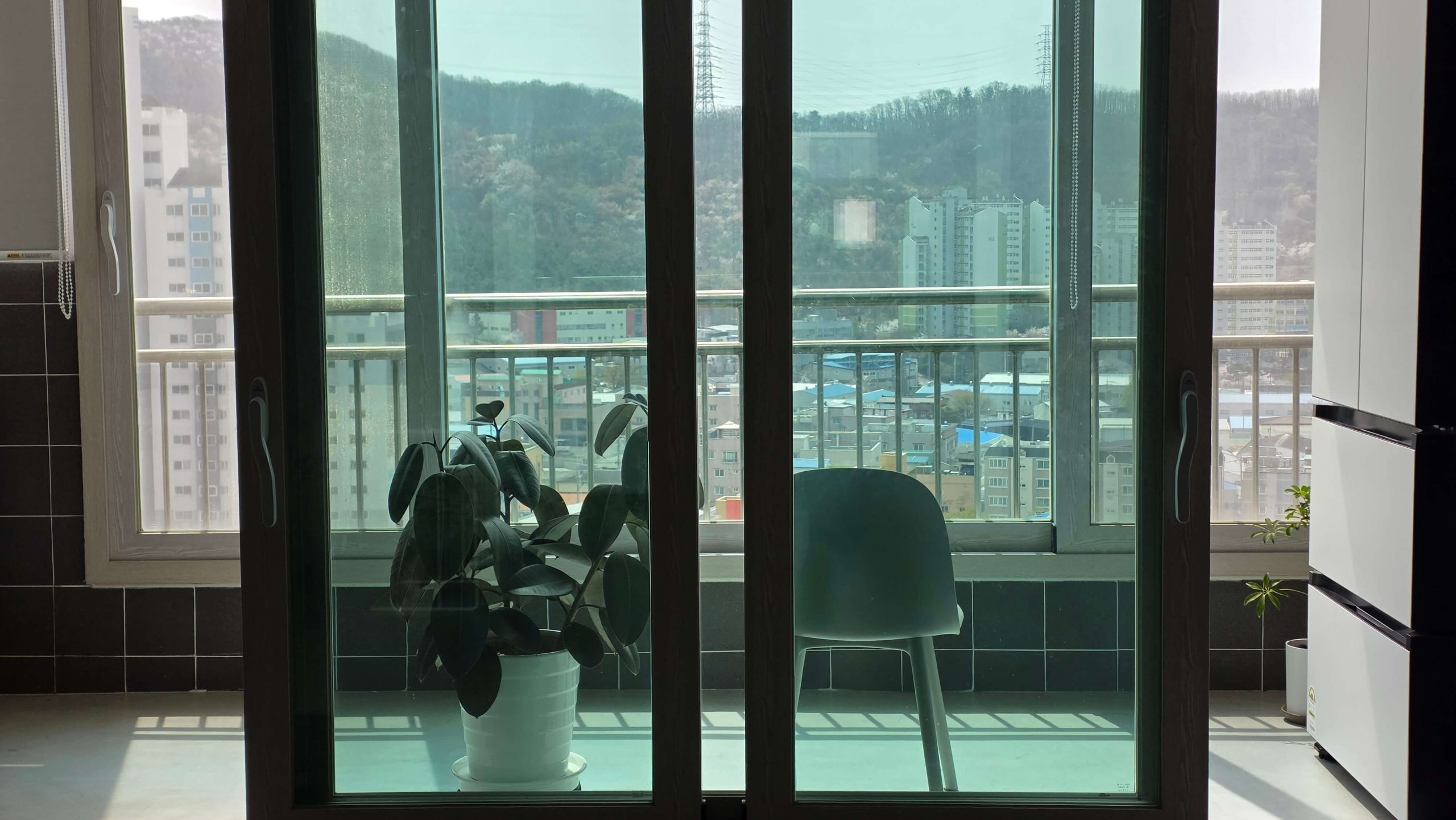 Soft sunlight entering a quiet balcony with a chair and indoor plants