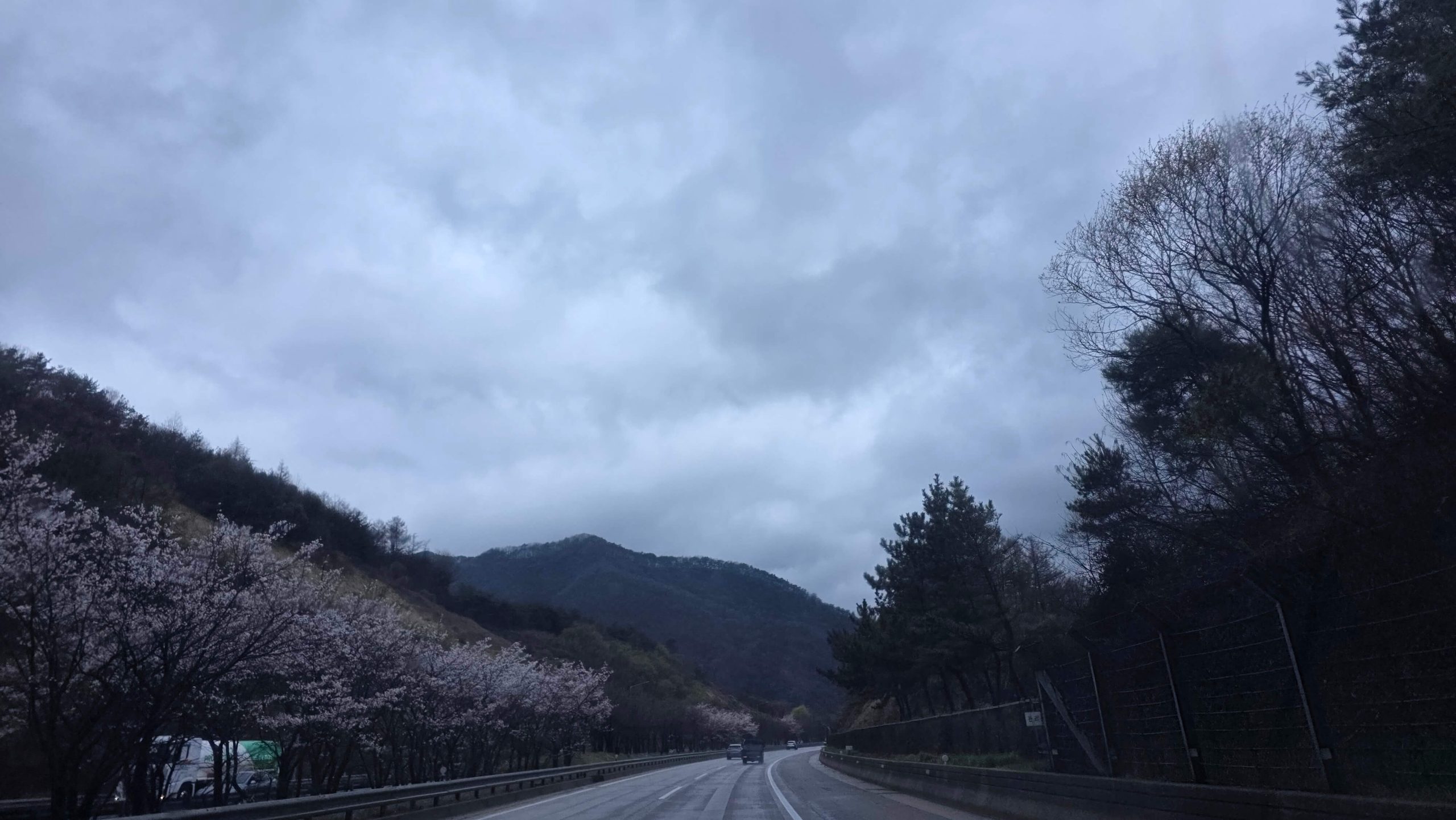 quiet road through mountains under a cloudy sky during a calm drive