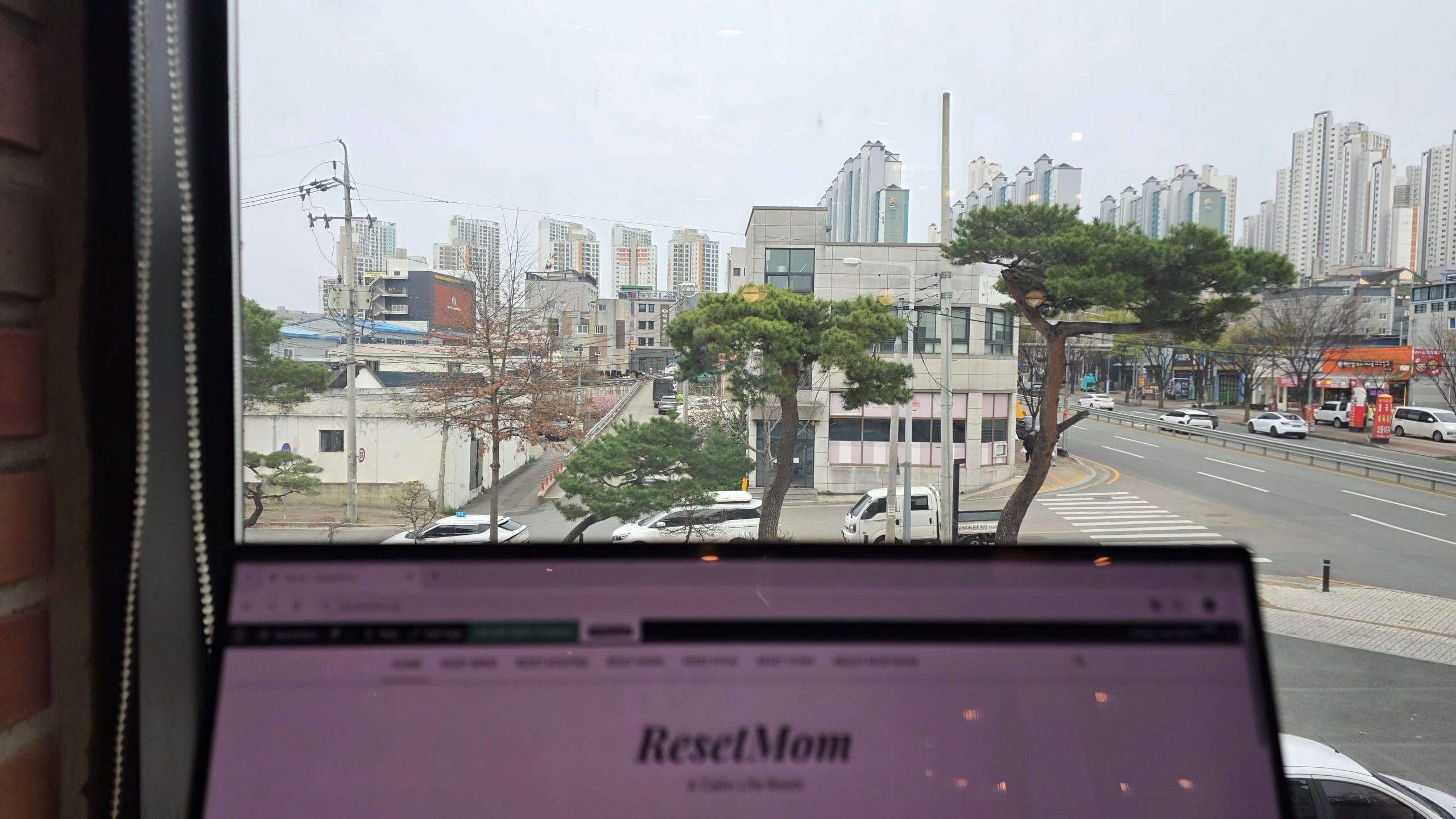 A quiet indoor moment with a laptop, looking out over a busy city street