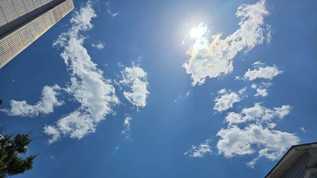 looking up at bright clouds in a clear blue sky