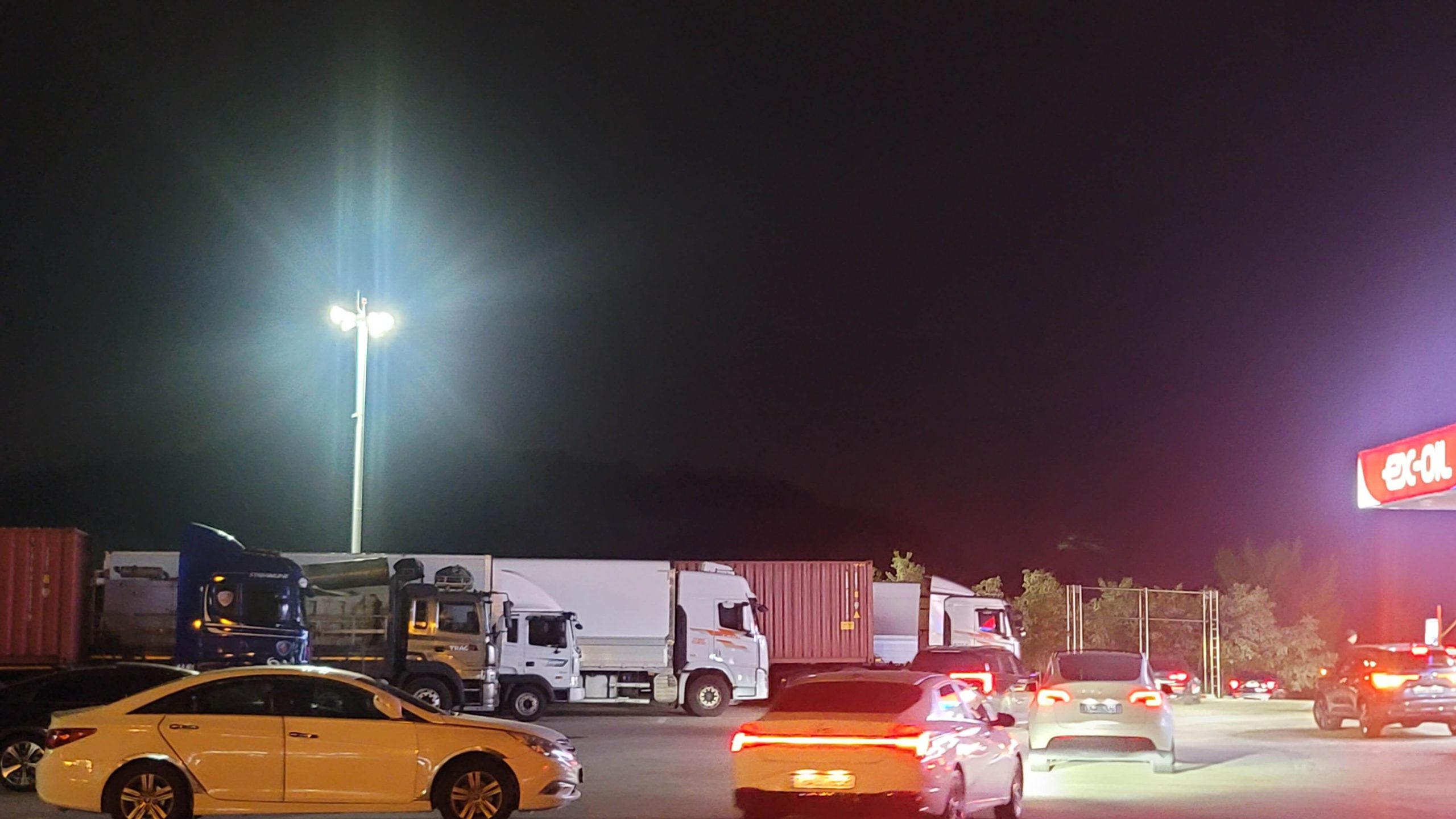 quiet nighttime highway rest stop with moving cars and soft traffic lights during a long drive