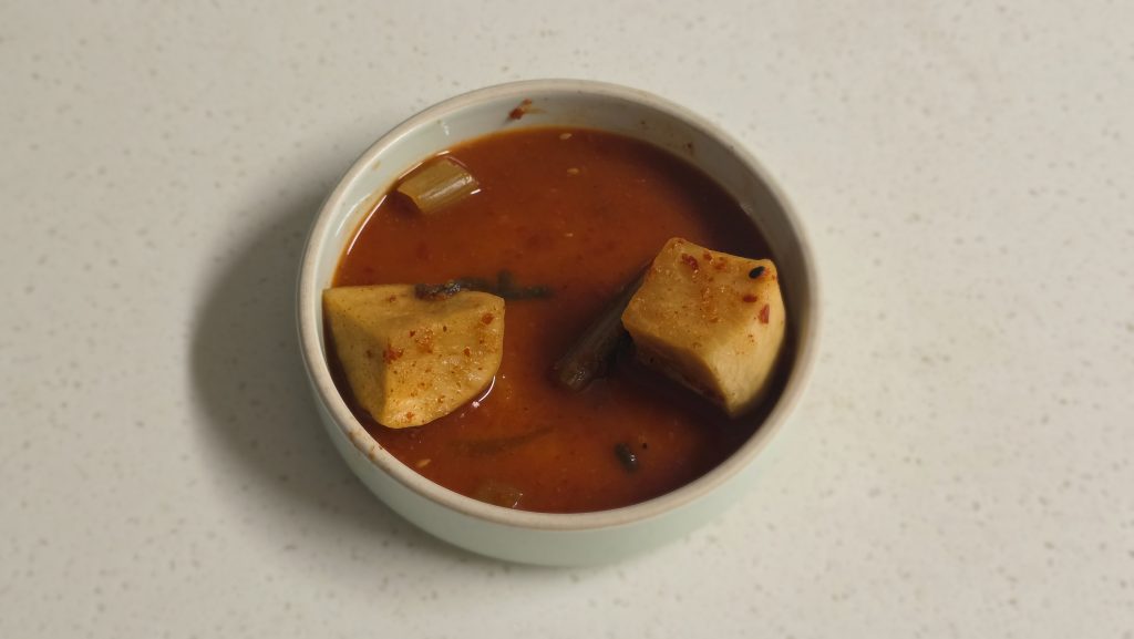 A few pieces of aged radish kimchi left in a bowl after a family meal.