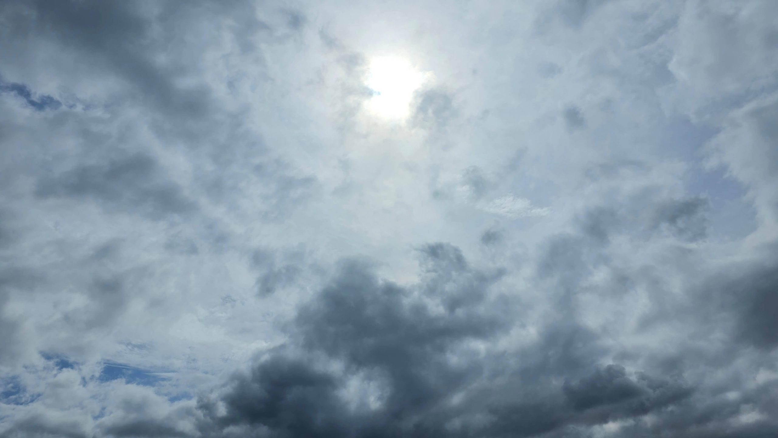 Clouds parting around soft sunlight in the afternoon sky.