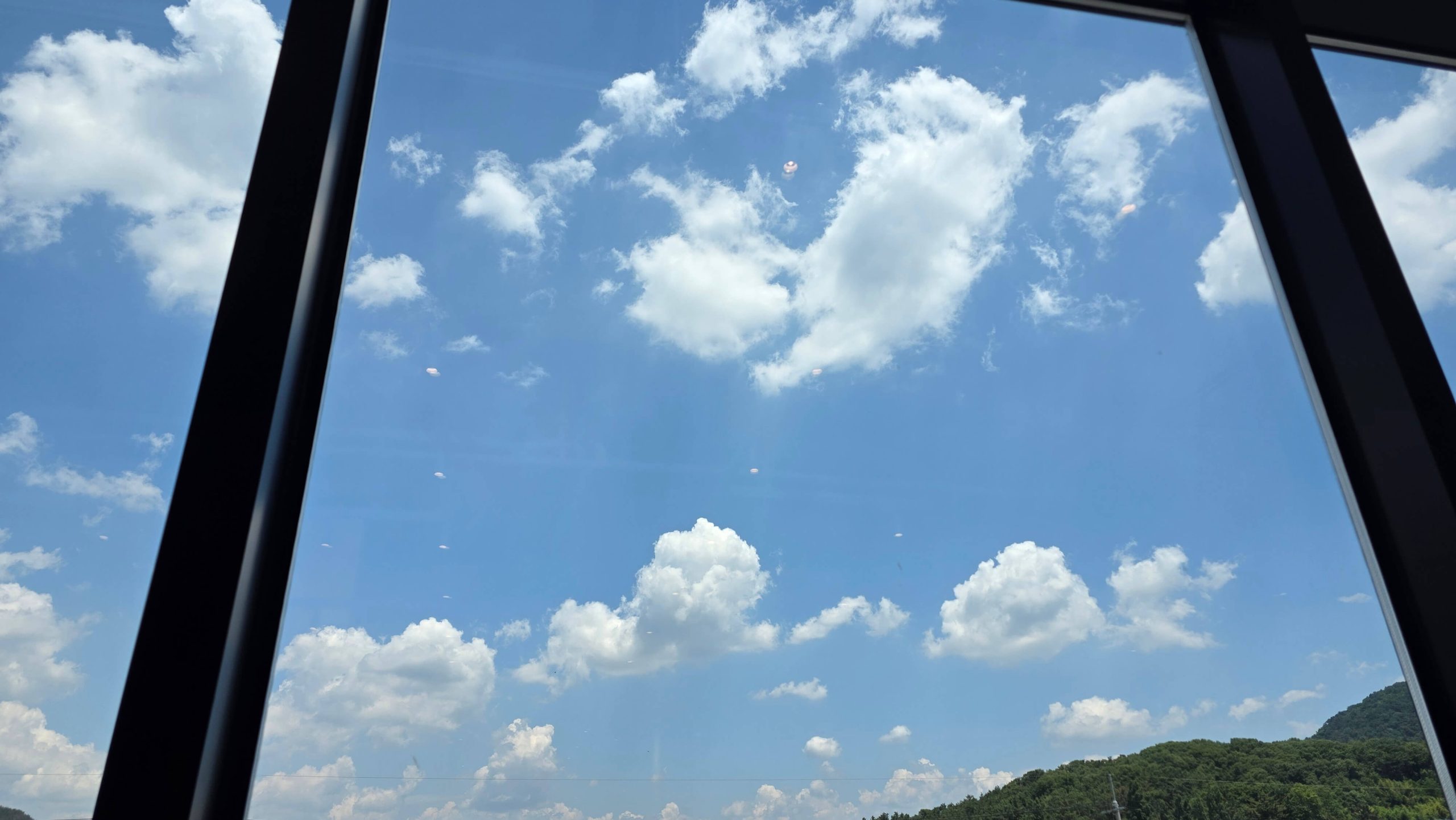 Blue sky and white clouds viewed through a large window, inviting a quiet pause and a moment to stop adjusting.
