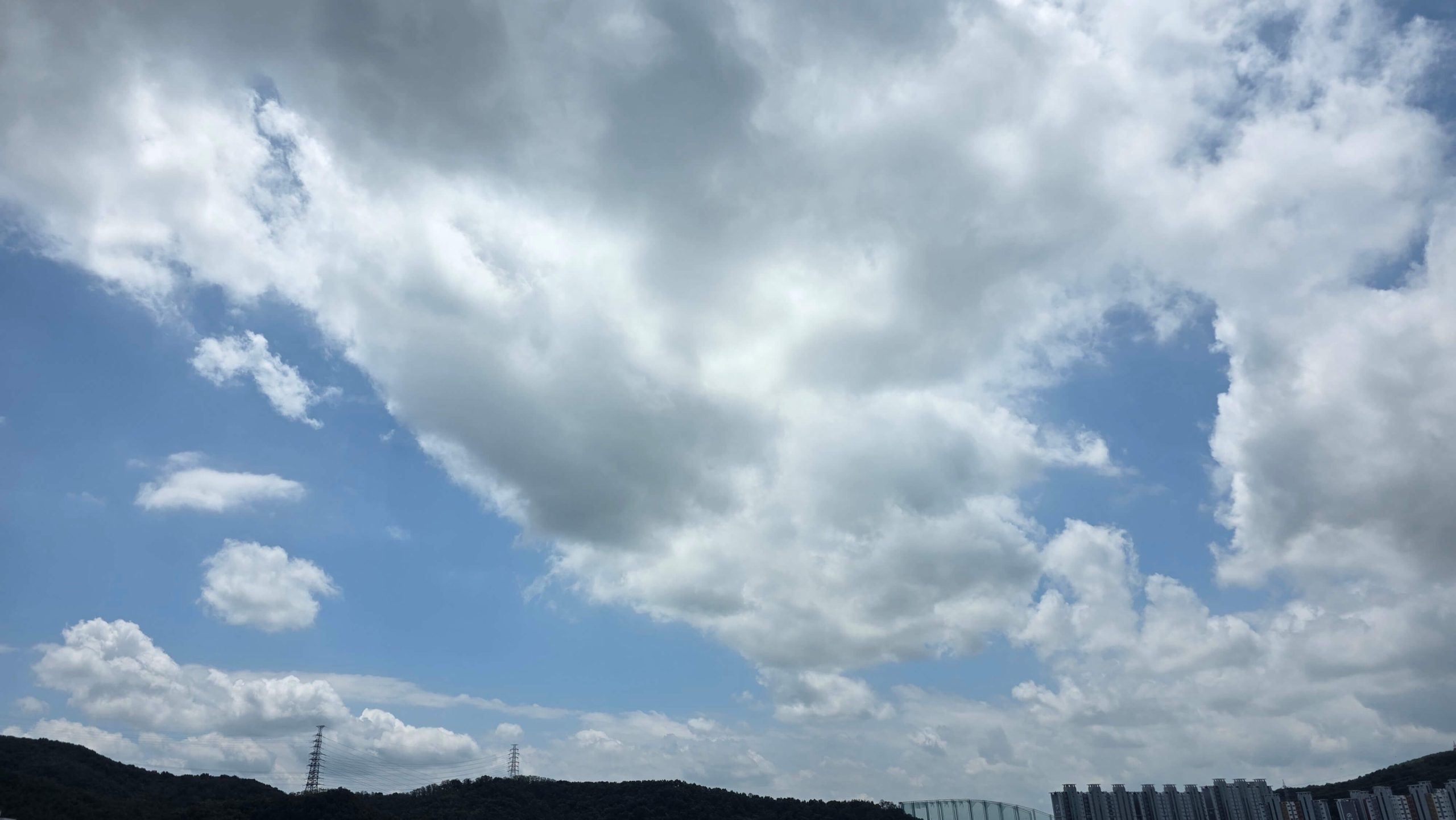 Dark clouds opening to blue sky above a quiet neighborhood, symbolizing seeing reality beyond old patterns.