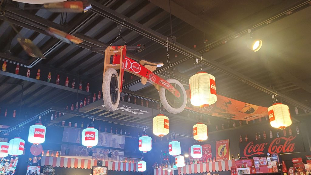 Vintage Coca-Cola bicycle and hanging Coca-Cola lantern lights inside a Coca-Cola themed cafe