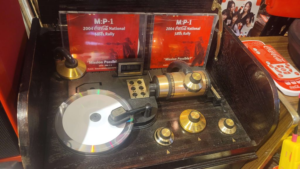 A vintage turntable still playing music inside a Coca-Cola collection.