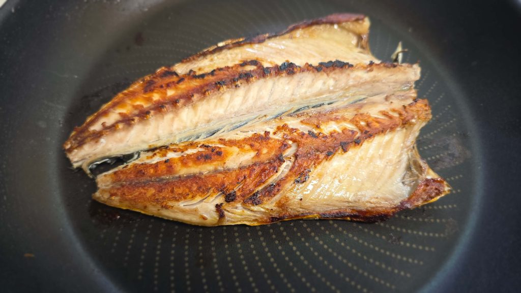 Grilled salted mackerel cooking in a frying pan