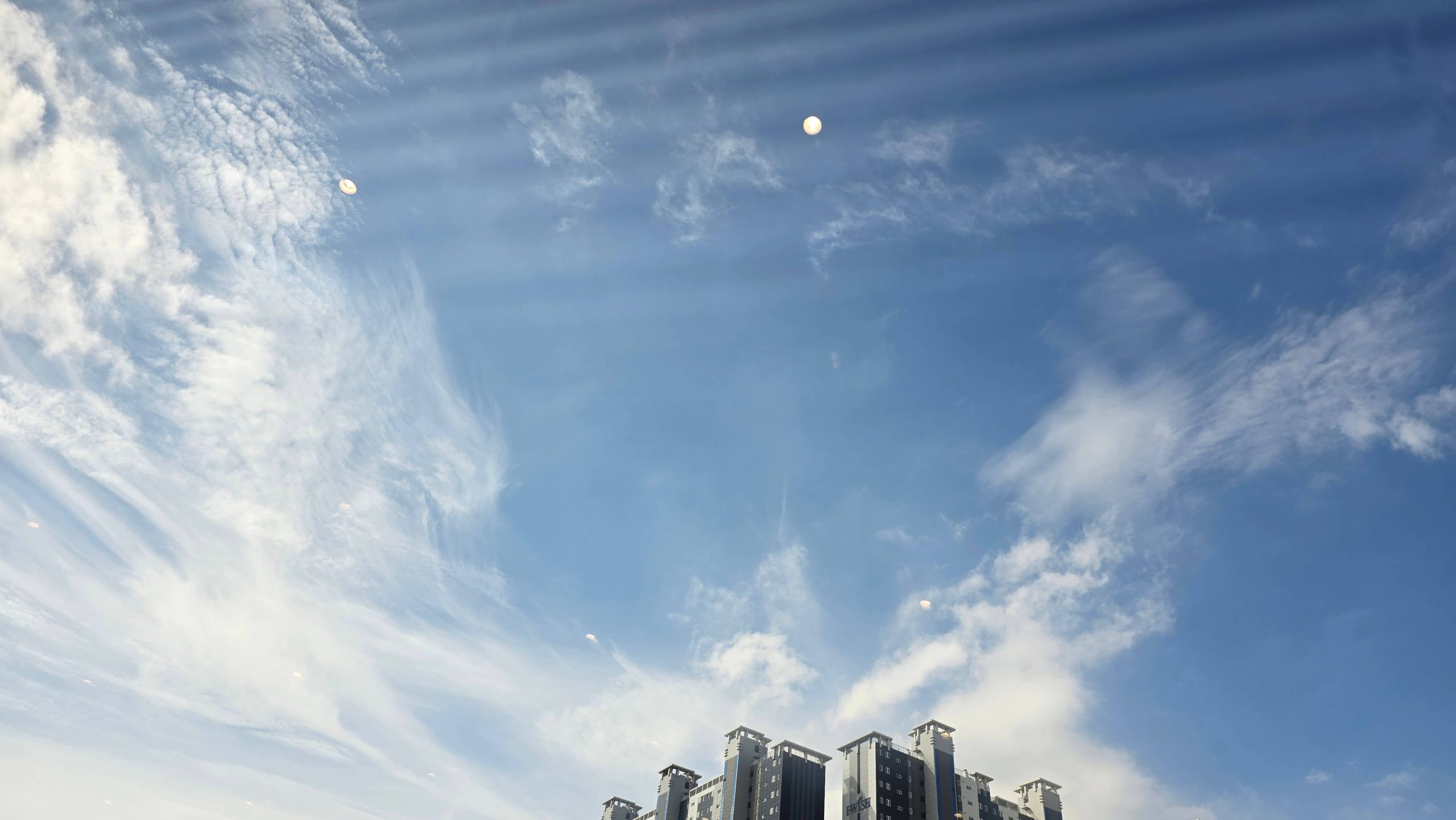 Open blue sky above apartment buildings on a quiet summer morning