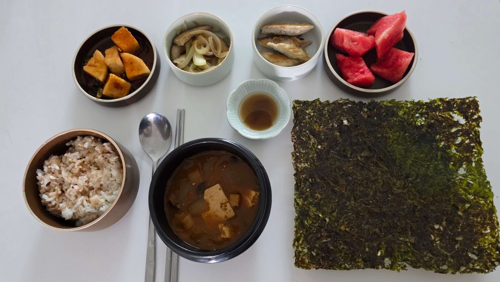 Lunch table with a small plate of leftover grilled mackerel and side dishes