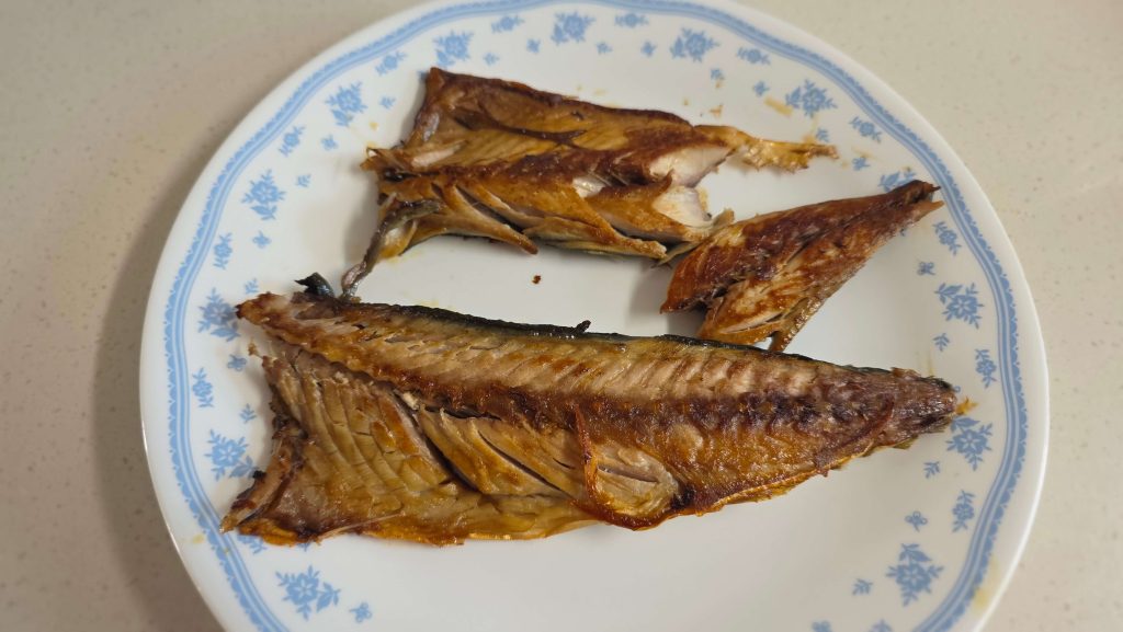 Grilled mackerel resting on a dinner plate at the end of the day