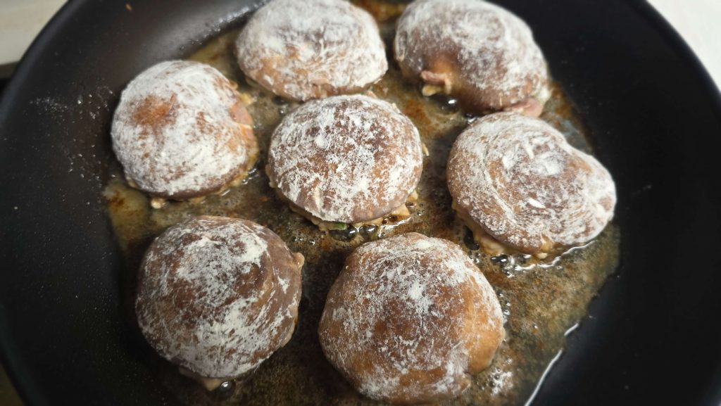 Stuffed shiitake mushrooms cooking in a frying pan