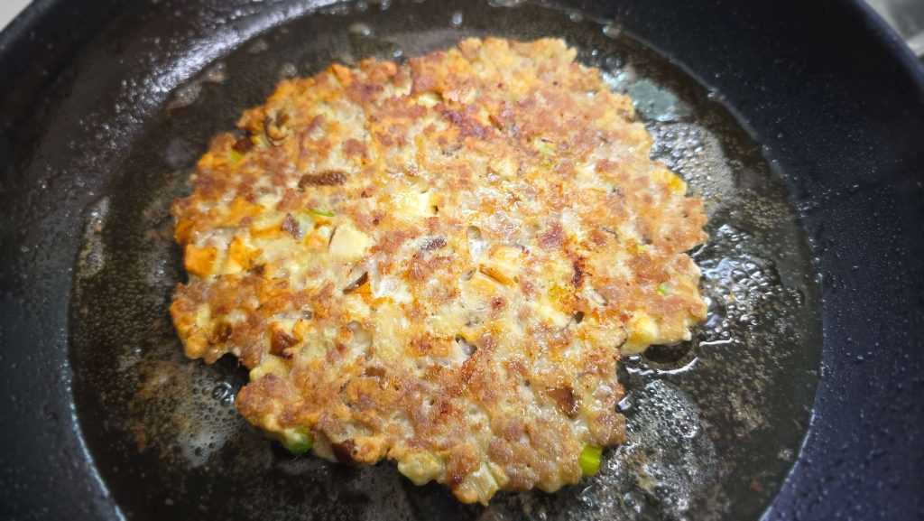 Small pork patty made from leftover filling cooking in a pan