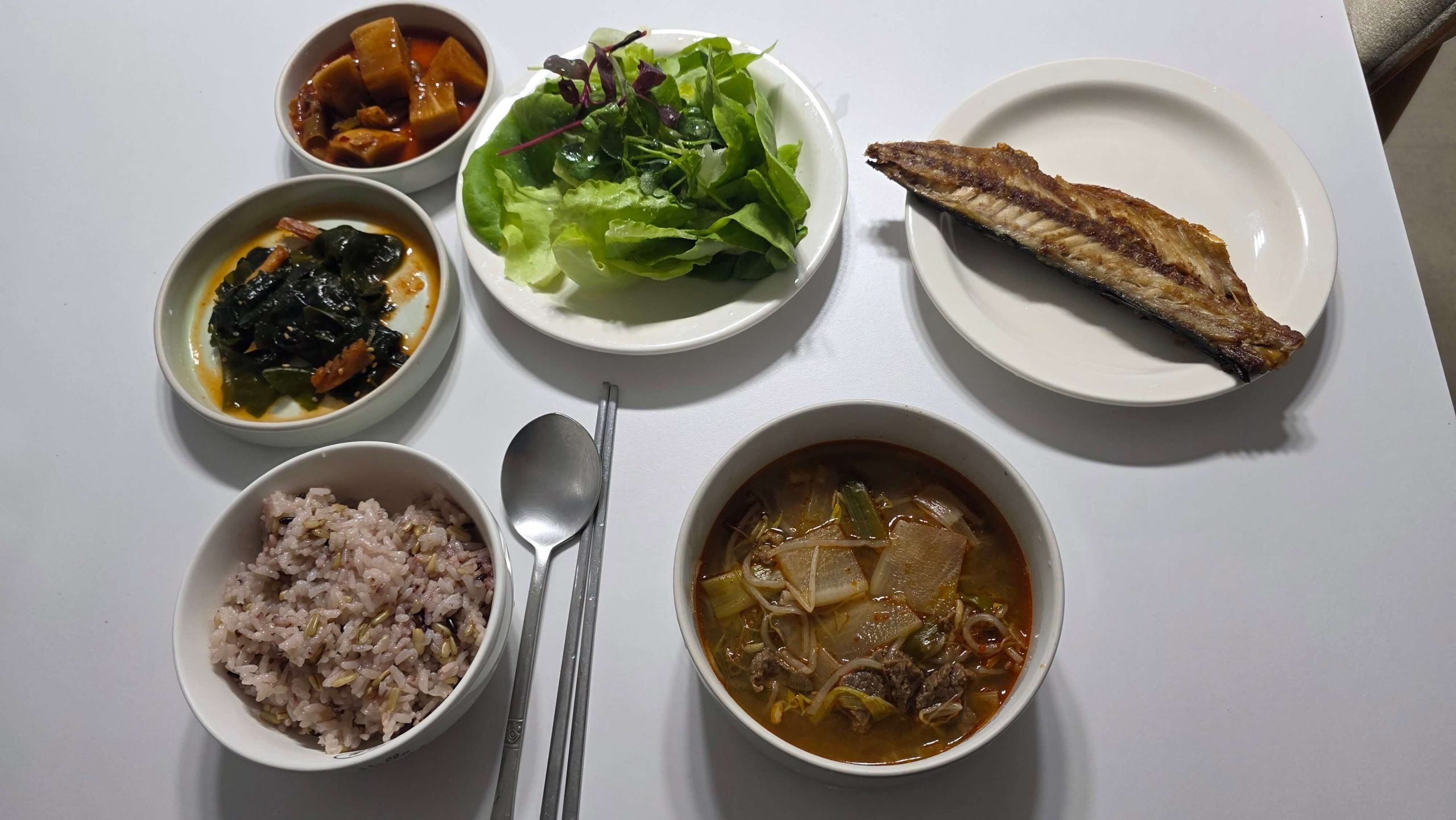 Simple dinner with spicy beef soup, grilled mackerel, rice, and side dishes