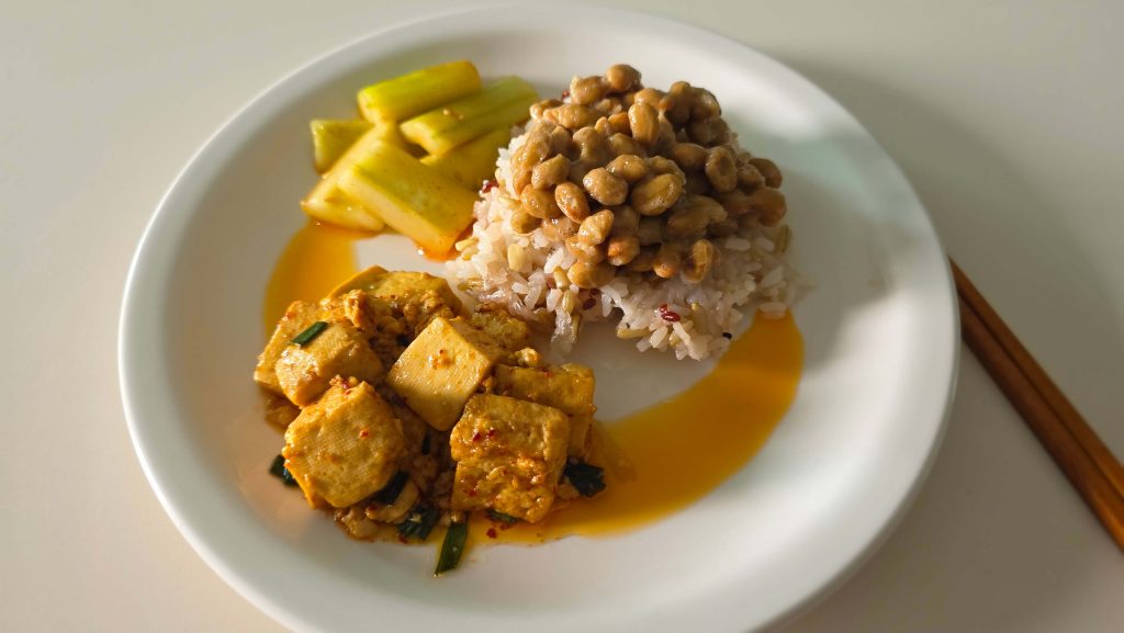 A simple meal with rice, natto, braised tofu, and cucumber