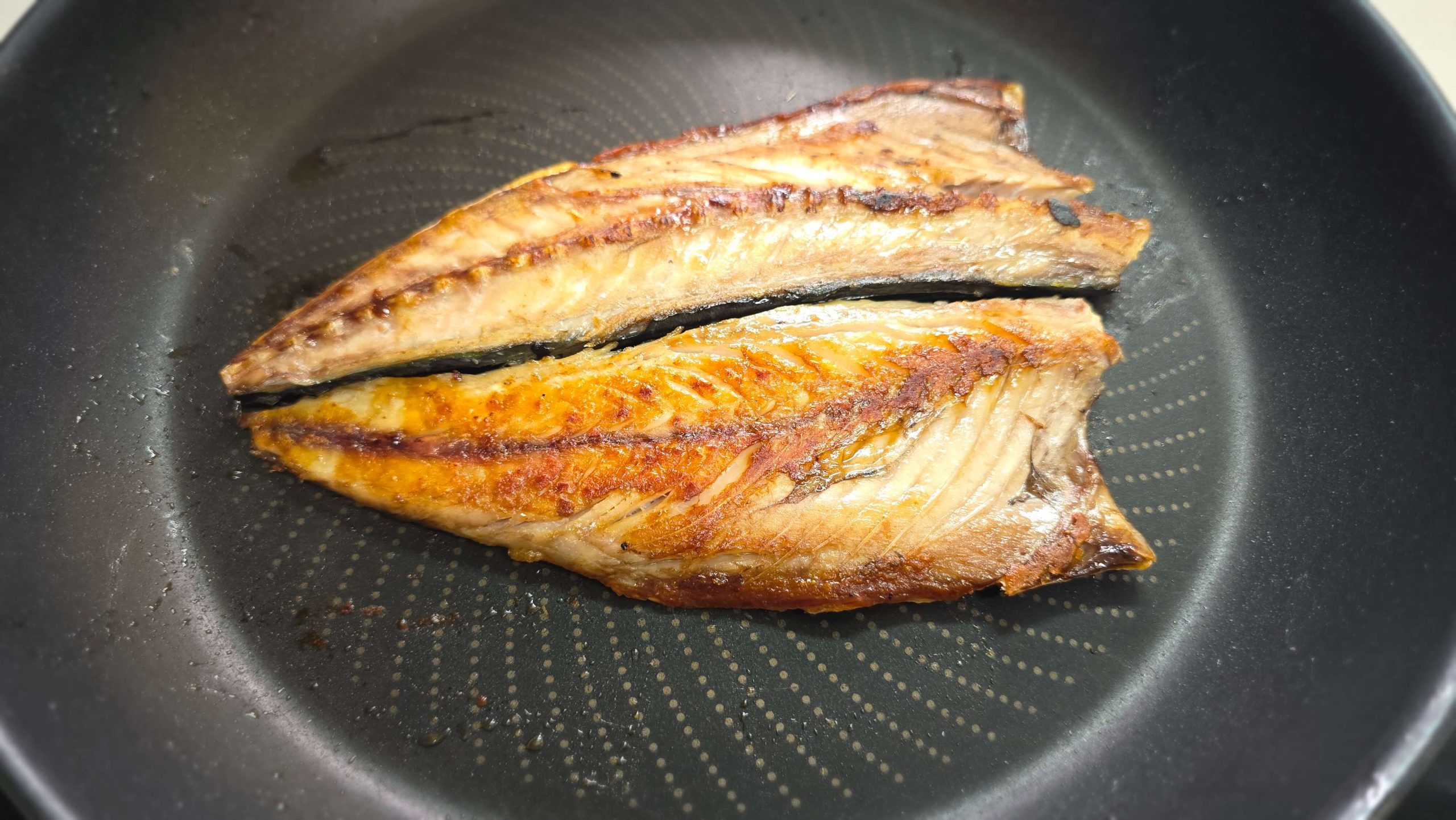 Golden grilled mackerel in a frying pan for a simple food lunch