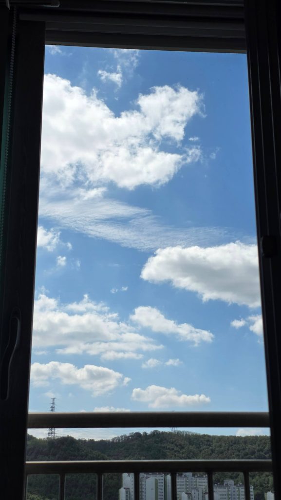 Blue sky and white clouds seen through the bedroom window while lying down