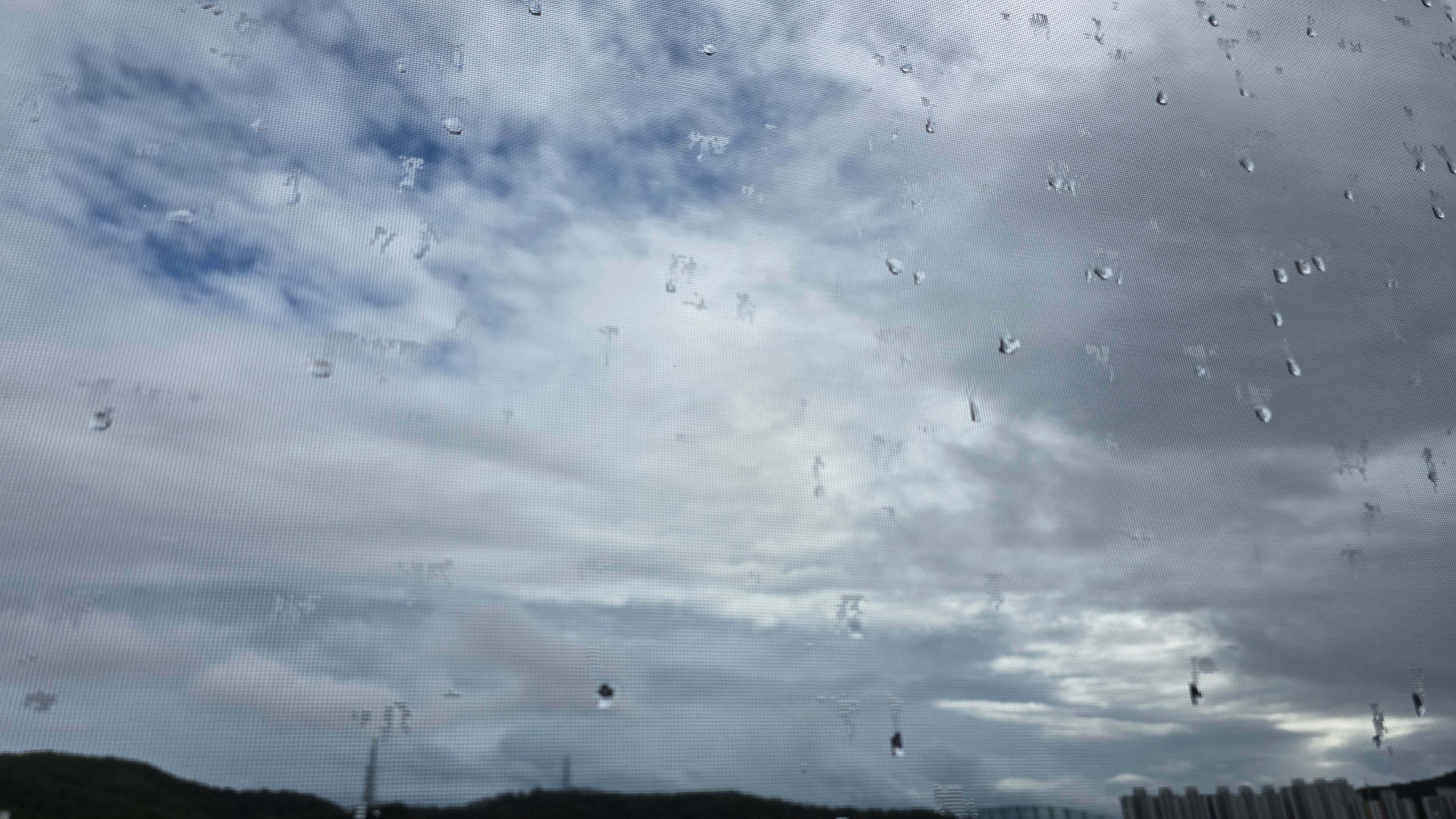 Raindrops on a window under a cloudy sky