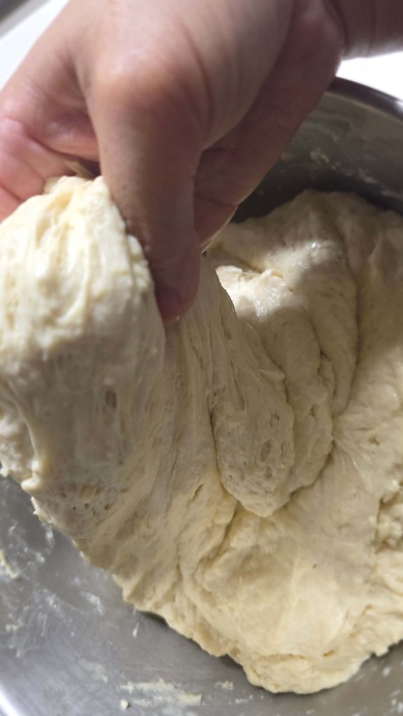 Folding bread dough by hand in a bowl