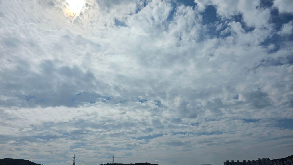 Blue sky filled with layers of white and gray clouds on a Sunday morning.