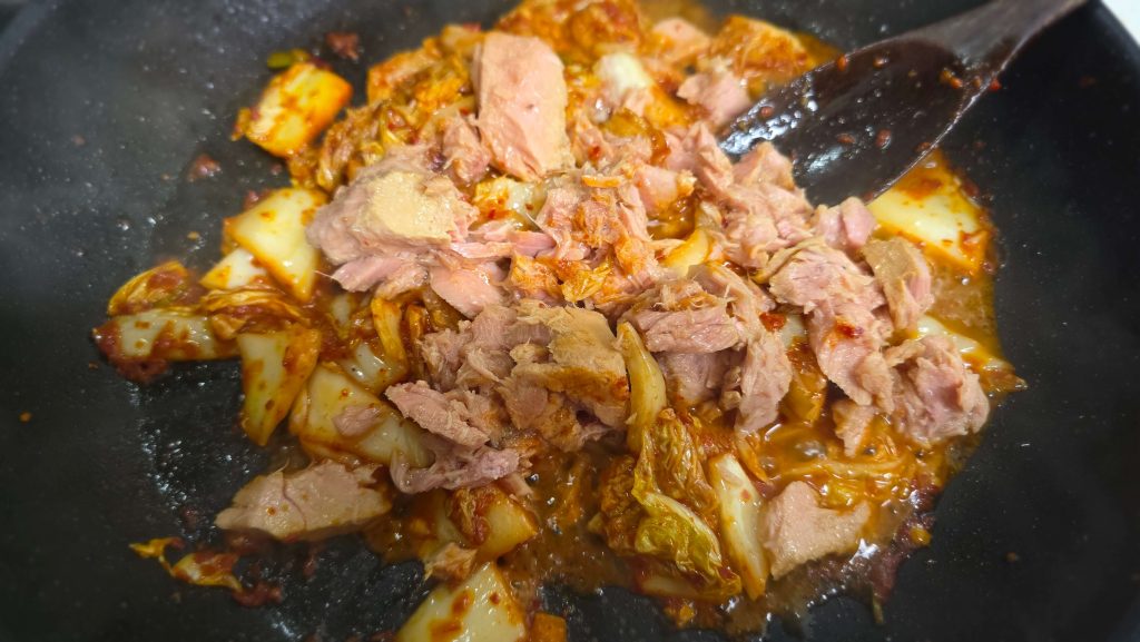 Tuna and napa cabbage kimchi cooking together in a frying pan