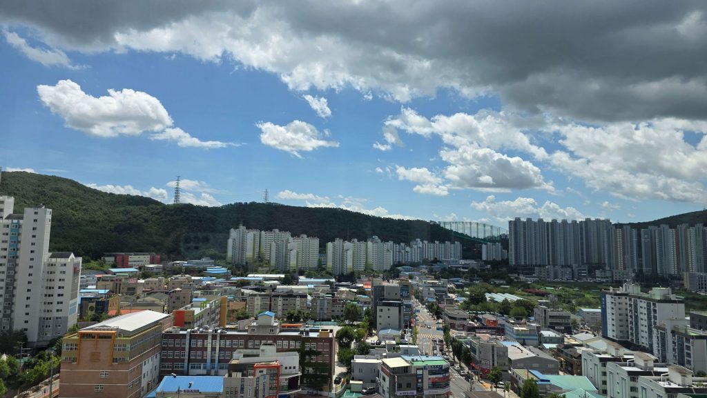 A wide view of mountains, apartment buildings, and a neighborhood of low-rise buildings from our top-floor apartment in Daegu.