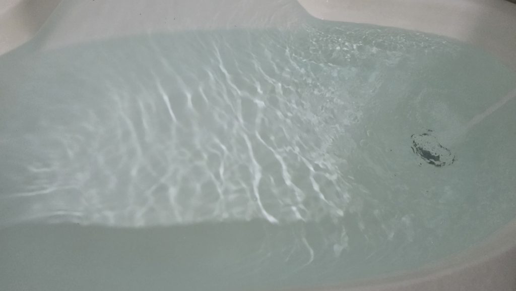 Gentle ripples and reflections of light on the water in a bathtub.