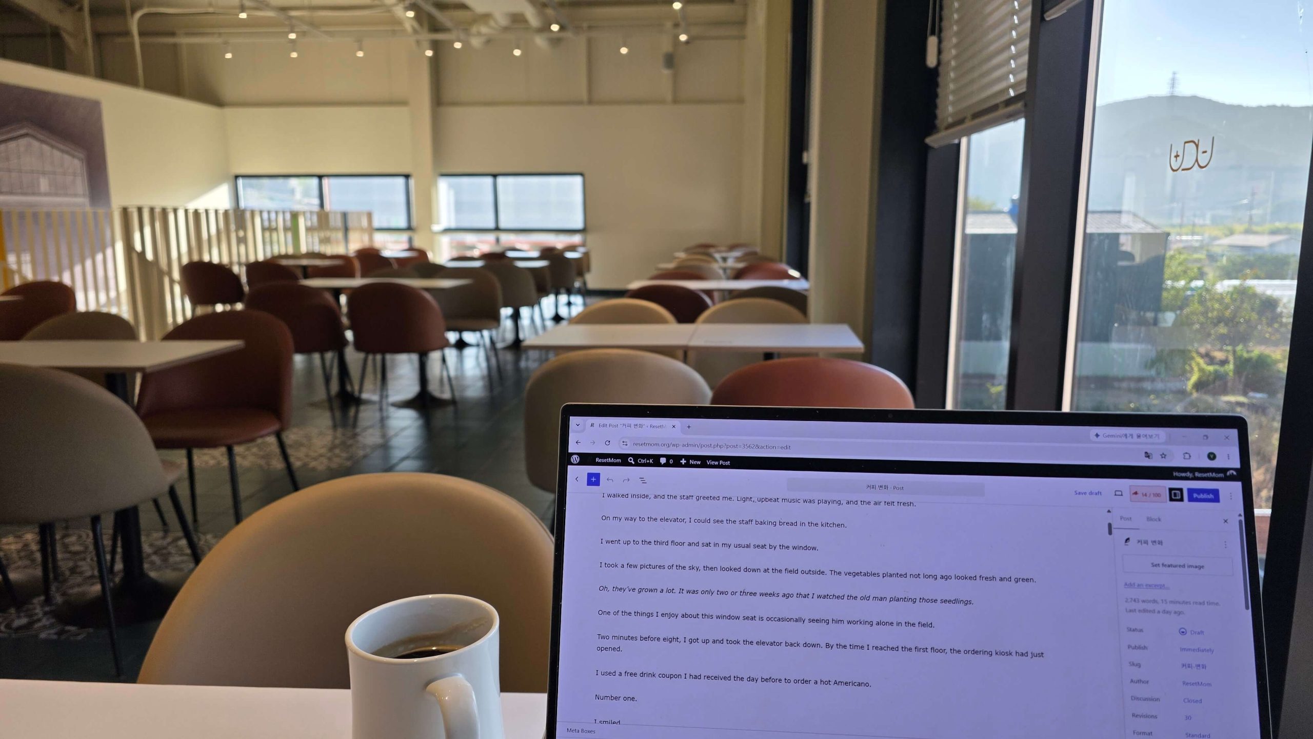 A cup of Americano beside a laptop in a quiet cafe on a sunny morning